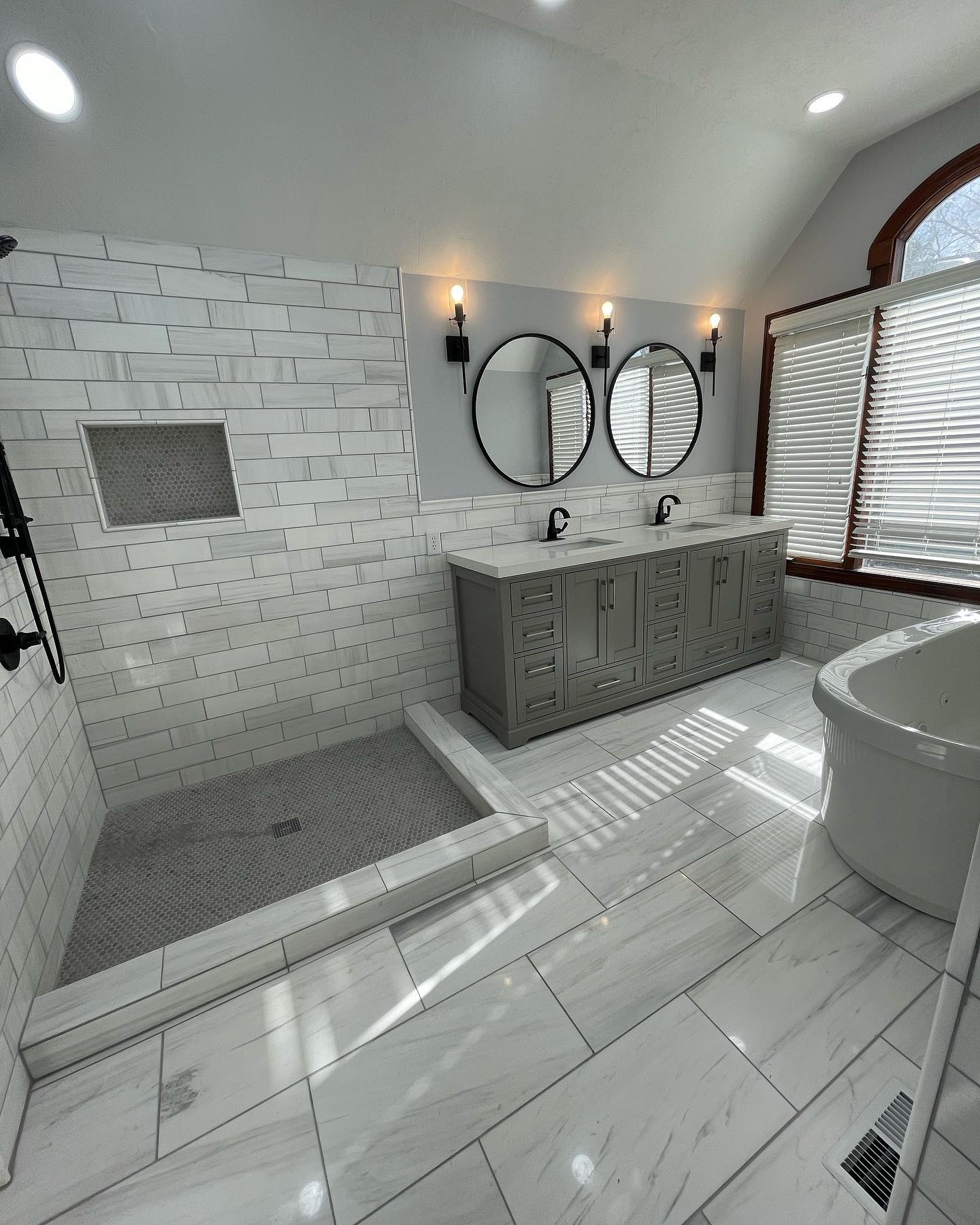 Luxury bathroom remodel with elegant gray wall and floor tile, custom shower installation, and double vanity in Indianapolis by Insta Pro Construction.